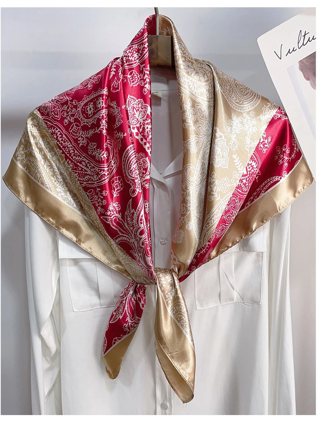 Beige and red paisley scarf tied over a white shirt on a hanger