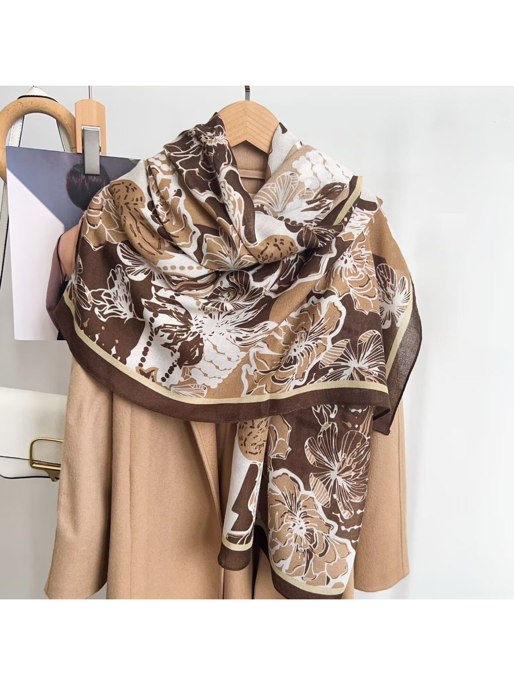 Brown floral scarf styled in a loose drape over a neutral coat