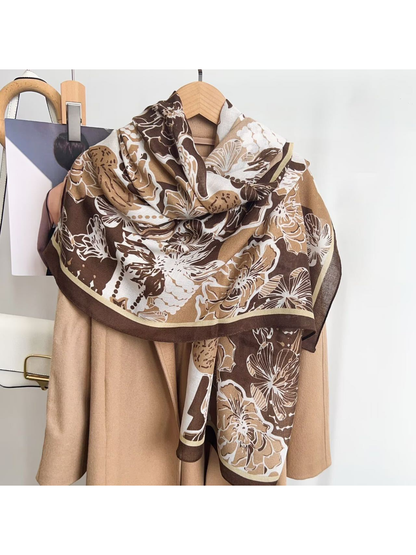 Brown floral scarf styled in a loose drape over a neutral coat