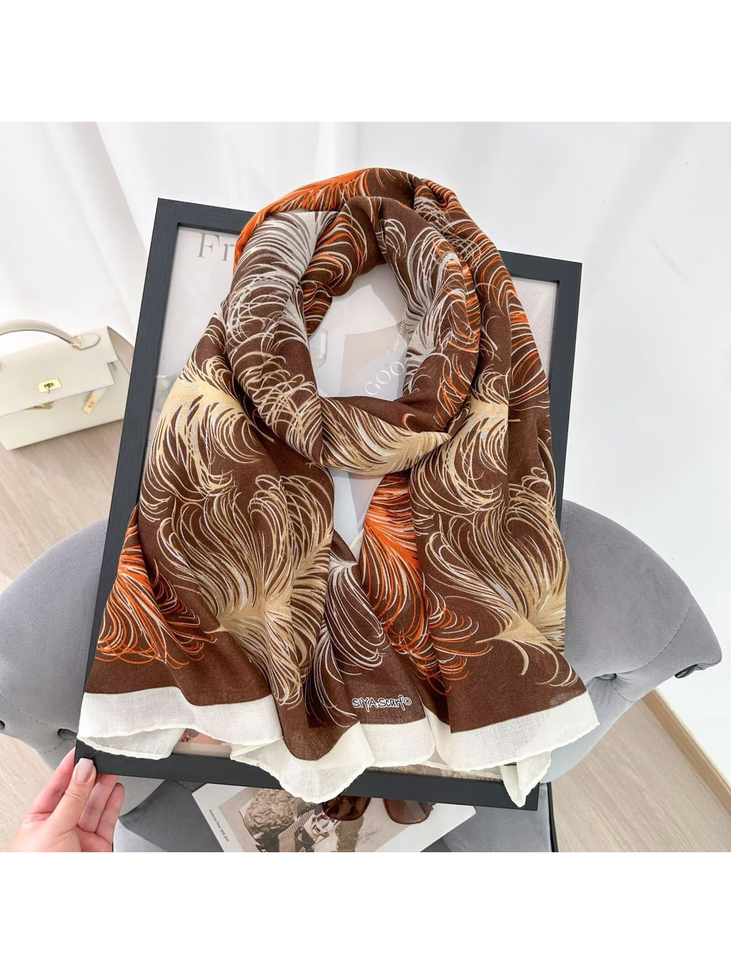 Coffee feather-pattern scarf arranged in a looped drape