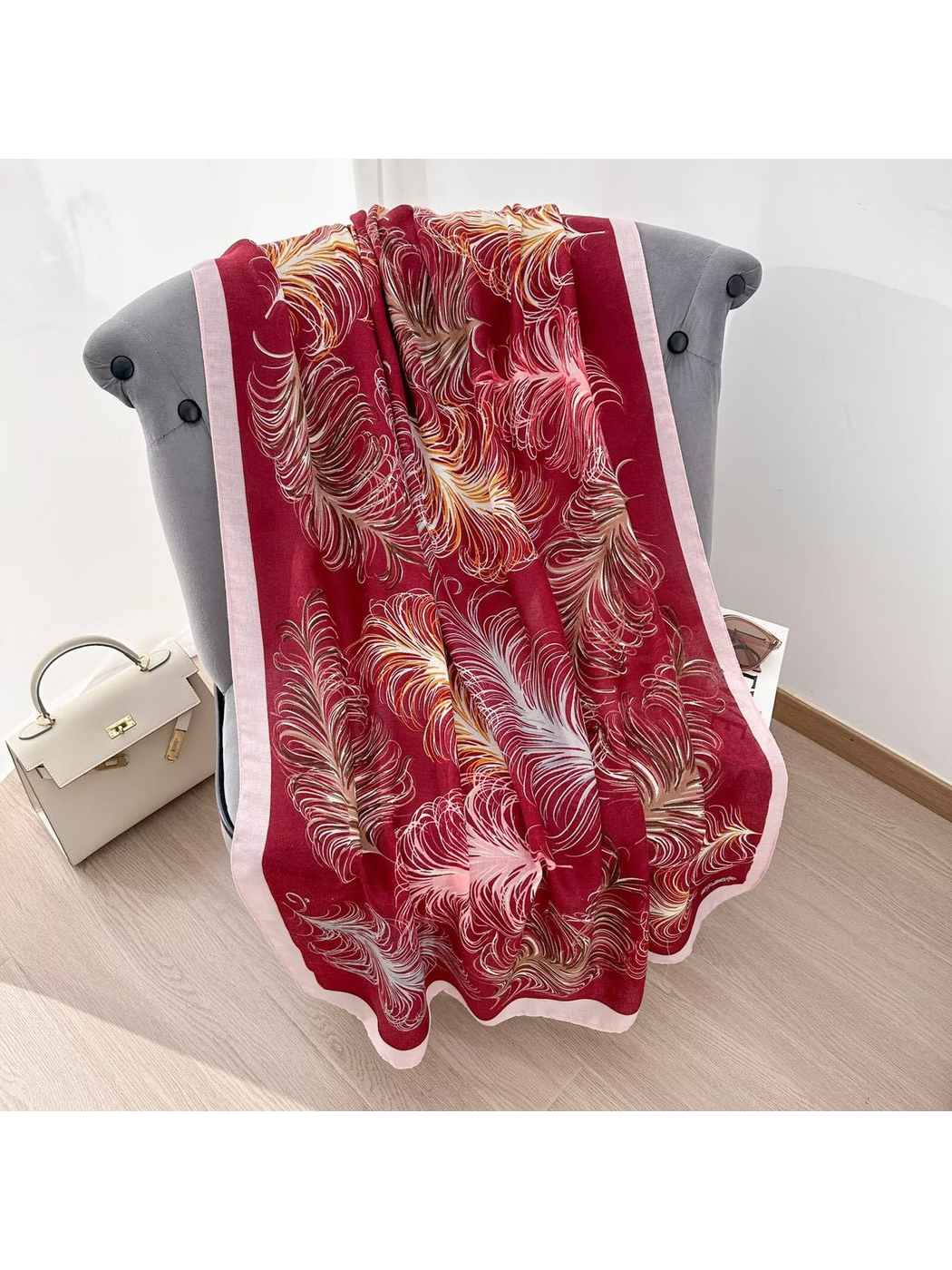 Burgundy feather-pattern scarf spread over a gray chair to show the full design