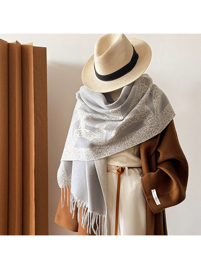 Gray geometric scarf styled as a shoulder wrap with fringed ends