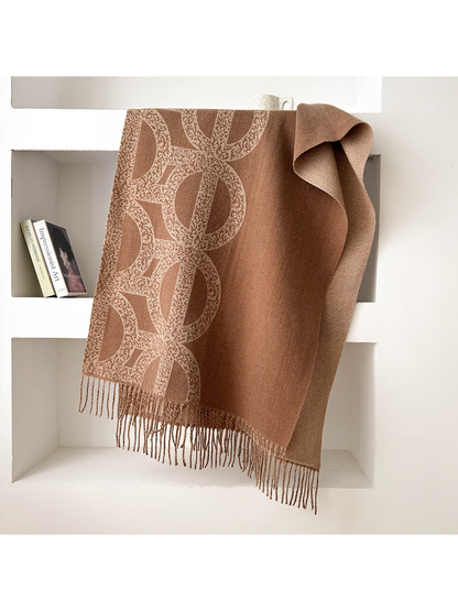Brown geometric scarf draped with a contrasting reverse and fringe