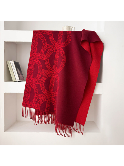 Red geometric scarf draped with a contrasting reverse and fringe