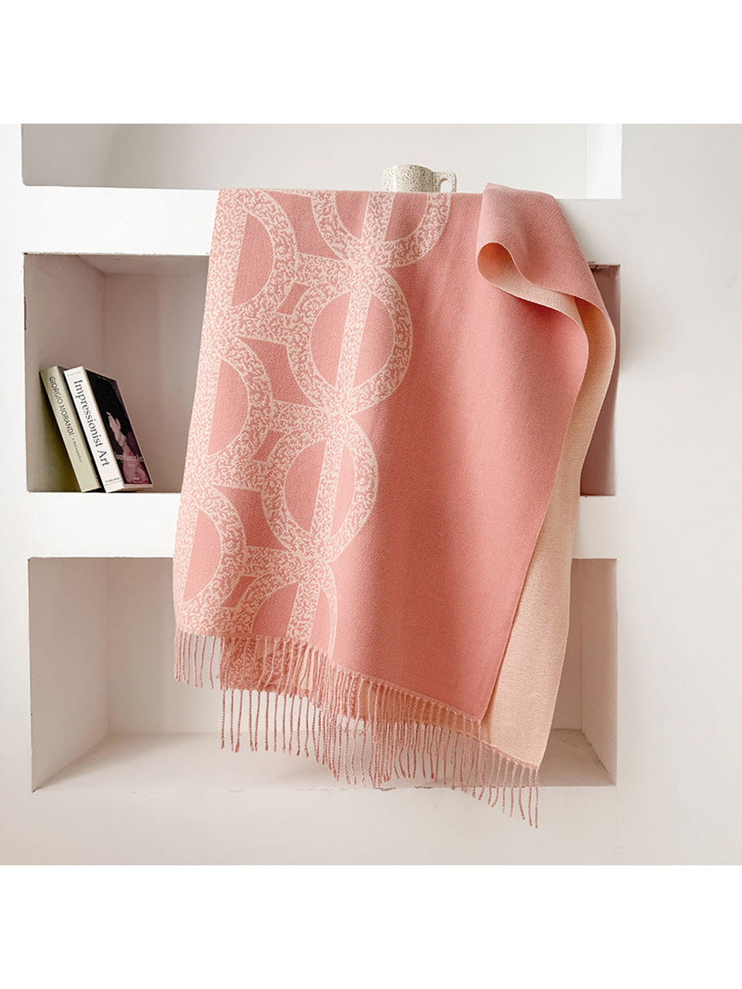 Pink geometric scarf draped with a contrasting reverse and fringe