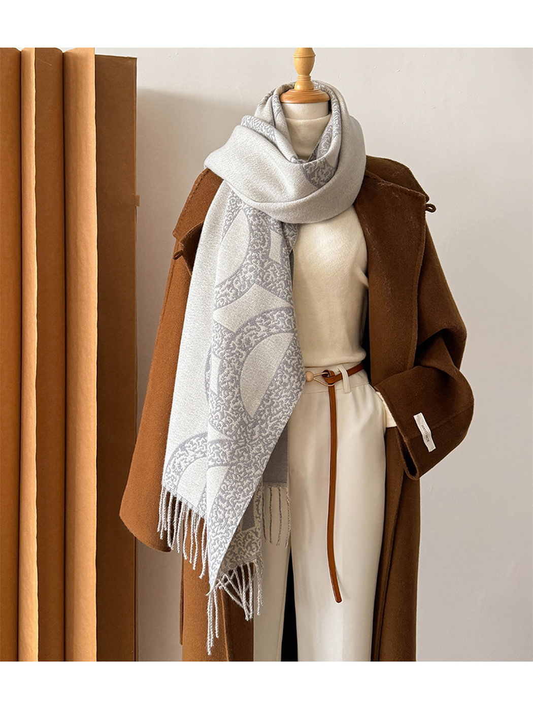 Gray geometric scarf looped and draped on a mannequin with fringed ends