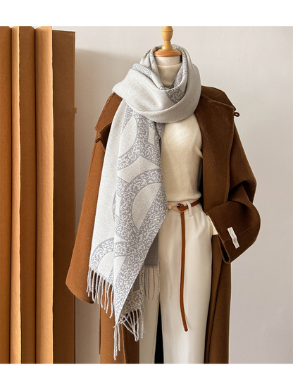 Gray geometric scarf looped and draped on a mannequin with fringed ends