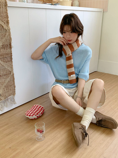 Model wearing the orange-and-cream striped scarf with a blue top