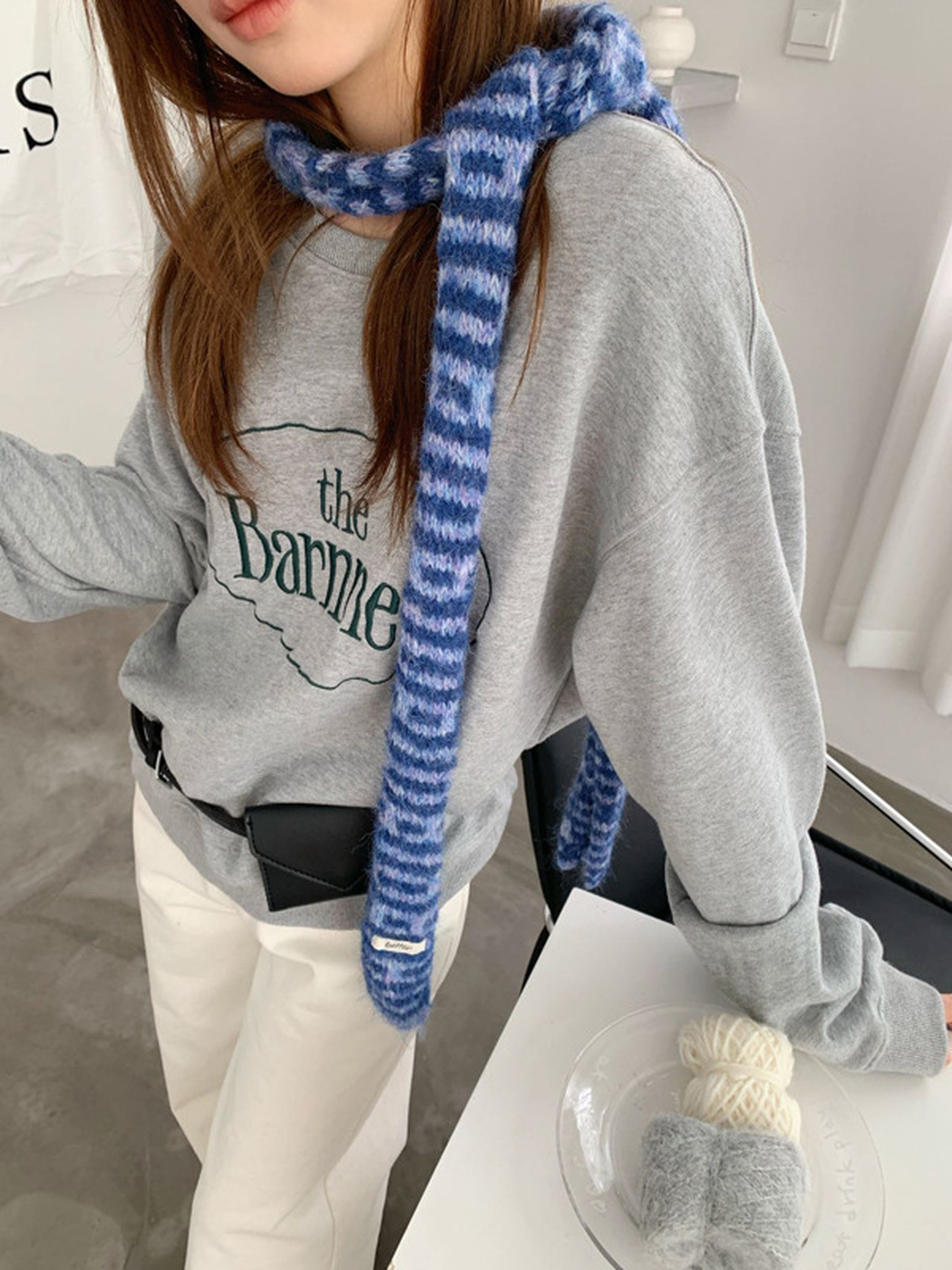 Blue striped scarf wrapped once around the neck with long ends hanging down