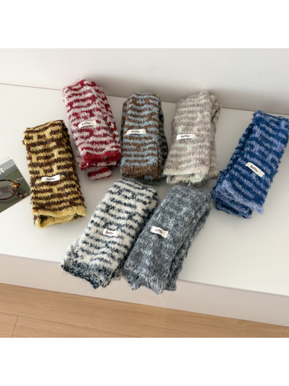 Seven fuzzy striped scarves in assorted colors displayed folded together