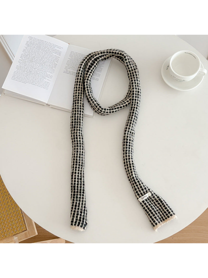Gray narrow check scarf arranged on a round table