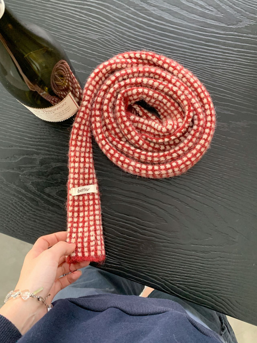 Red check scarf rolled to show its narrow shape and patterned surface