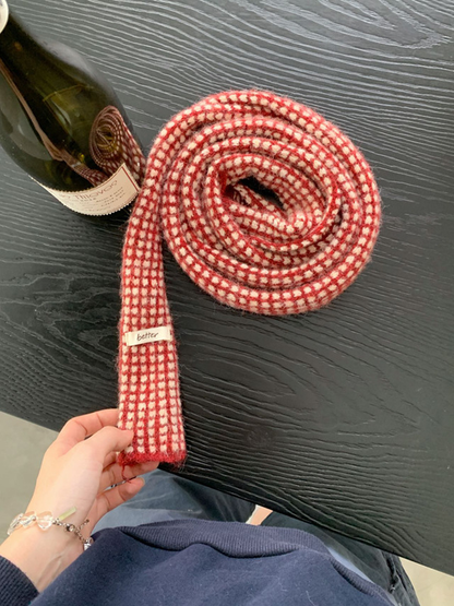 Red check scarf rolled to show its narrow shape and patterned surface