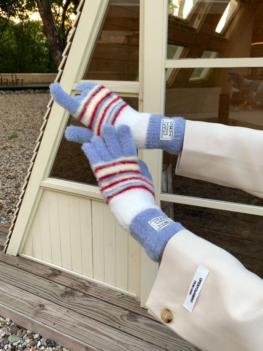 Close-up of Light Blue fuzzy fingerless gloves with white panels and red stripes