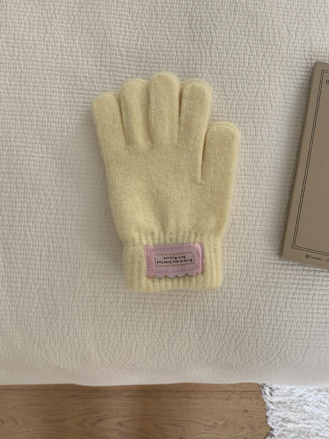 Yellow fuzzy knit gloves with ribbed cuffs and pink labels