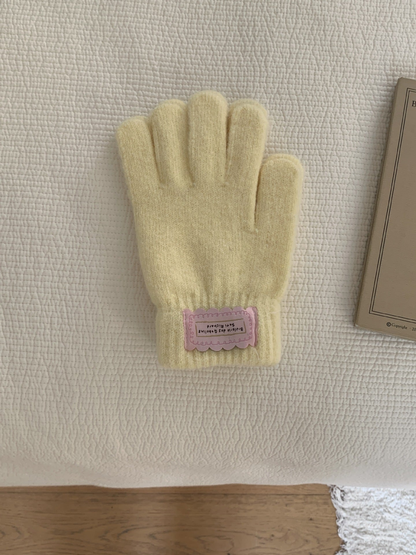 Yellow fuzzy knit gloves with ribbed cuffs and pink labels