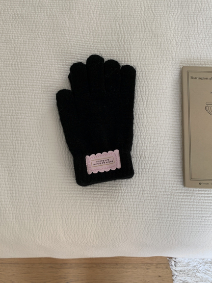 Black fuzzy knit gloves with ribbed cuffs and pink labels