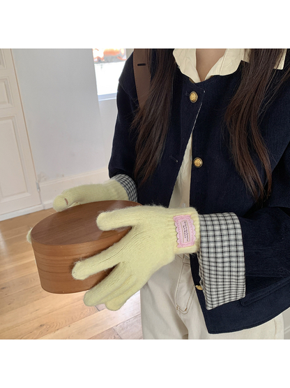 Yellow fuzzy knit gloves worn while holding a round wooden box