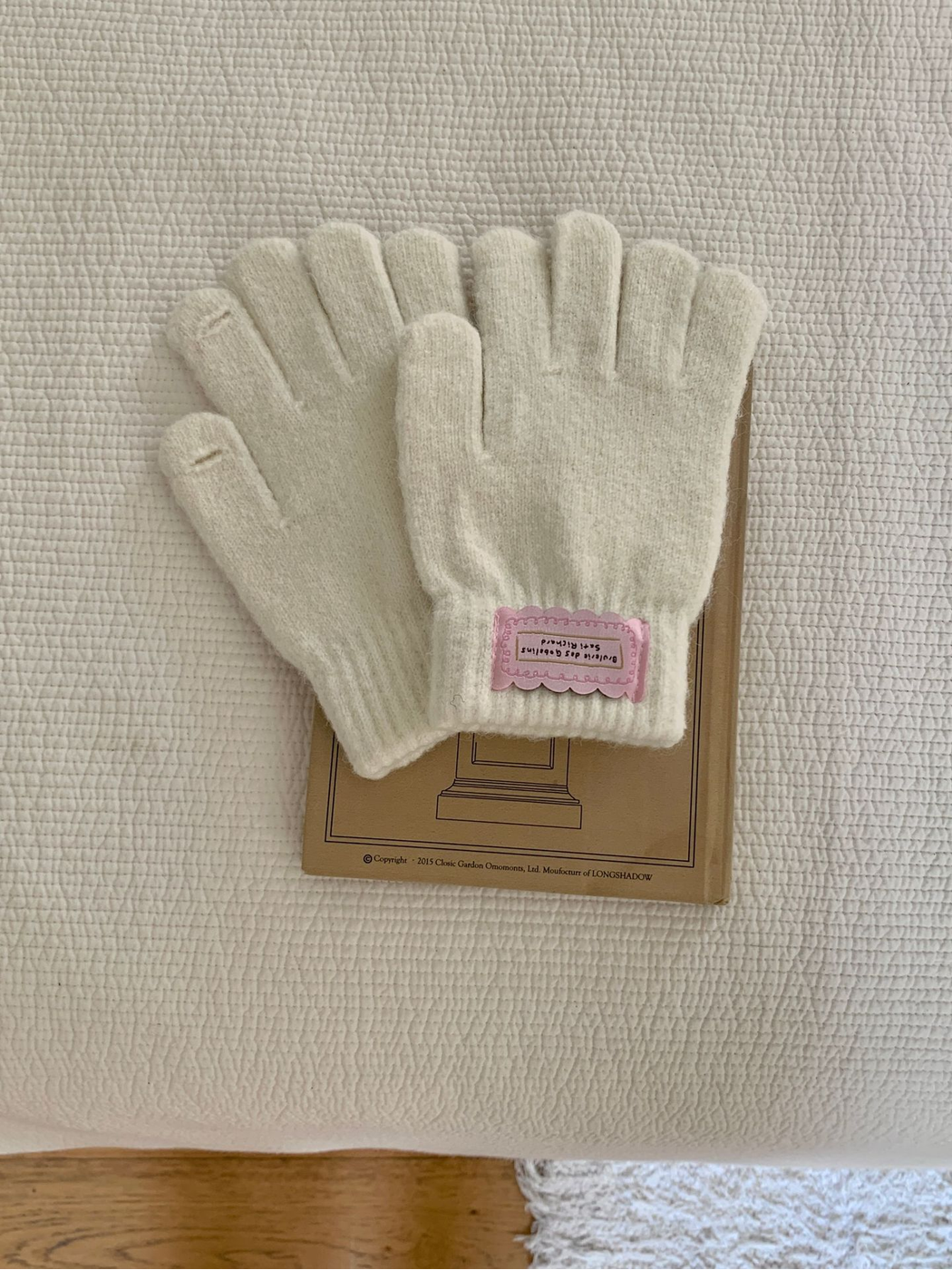 Ivory fuzzy knit gloves showing small openings at the thumb and index fingertips