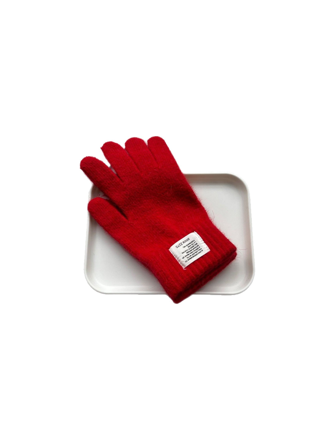 Red fuzzy knit gloves with ribbed cuffs displayed on a white tray