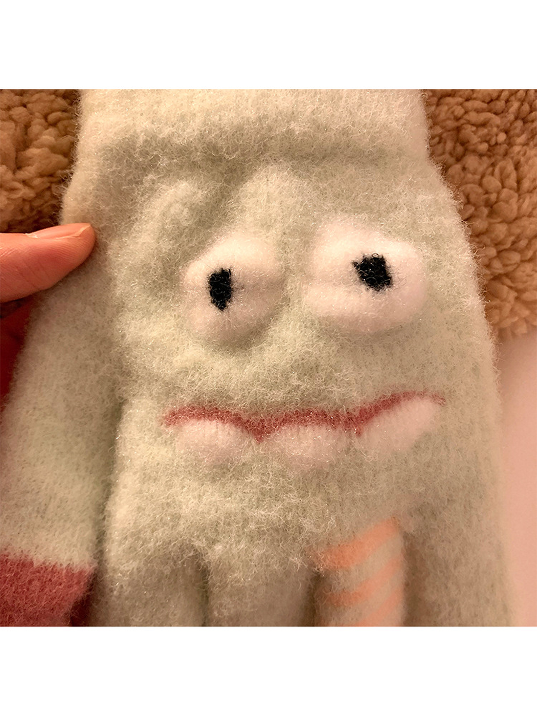 Close-up of the raised fuzzy eyes and mouth on the Mint gloves