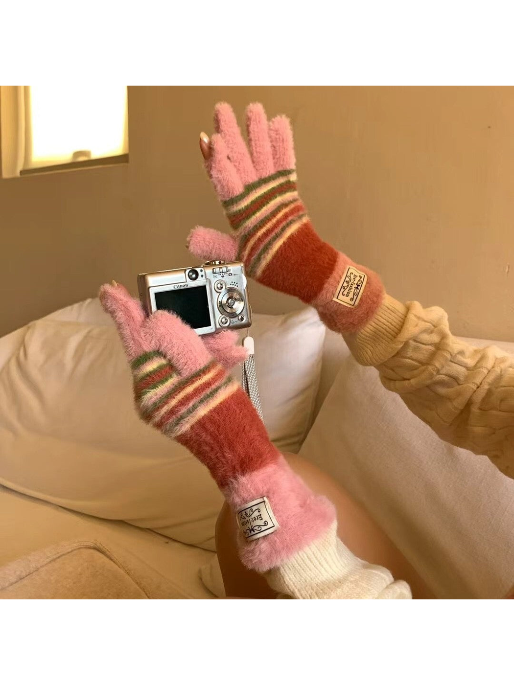 Pink fuzzy striped gloves styled while holding a compact camera