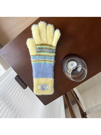 Yellow fuzzy gloves with light blue and green stripes, tabletop view