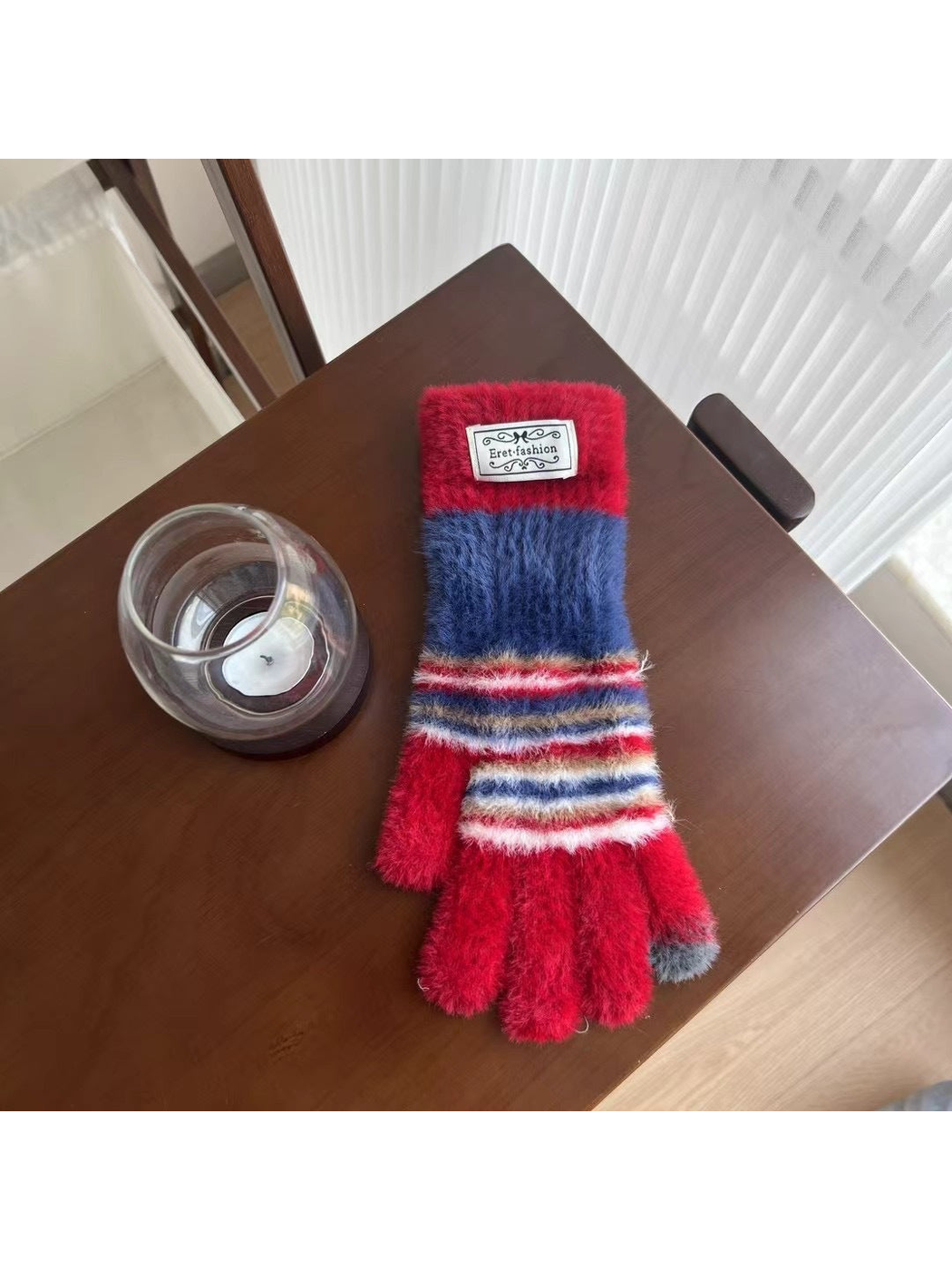 Red fuzzy gloves with navy panels and multicolor stripes, tabletop view