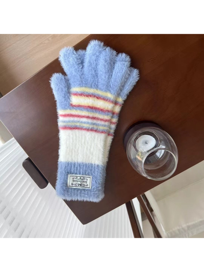Light Blue fuzzy gloves with white panels and multicolor stripes, tabletop view