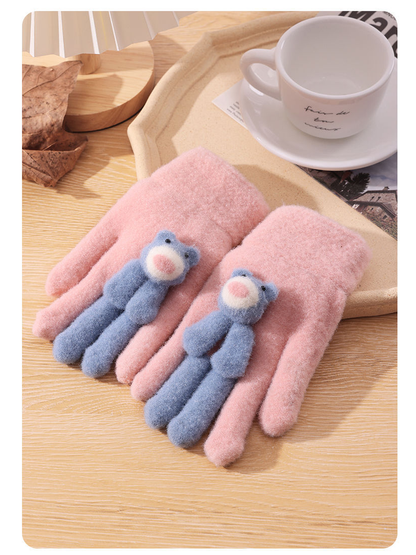 Pink fuzzy gloves with blue teddy bear appliques, tabletop view