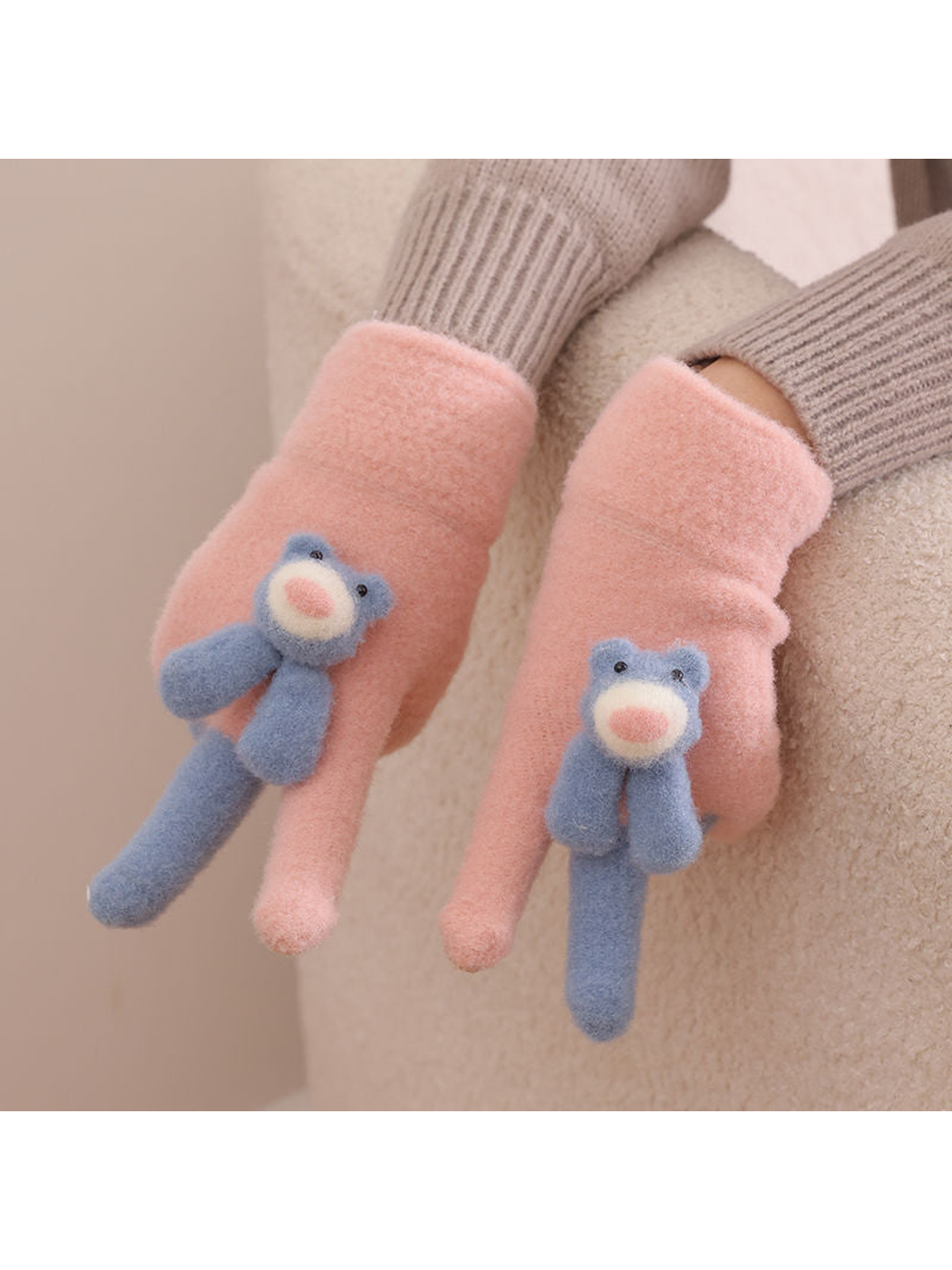 Pink fuzzy gloves with blue teddy bear appliques worn with a neutral sweater