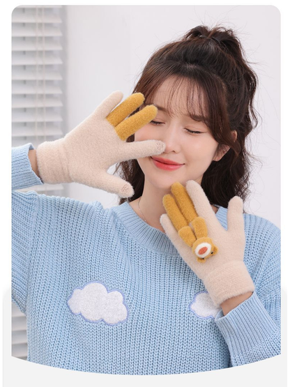 Beige fuzzy gloves with mustard teddy bear appliques worn with a blue sweater