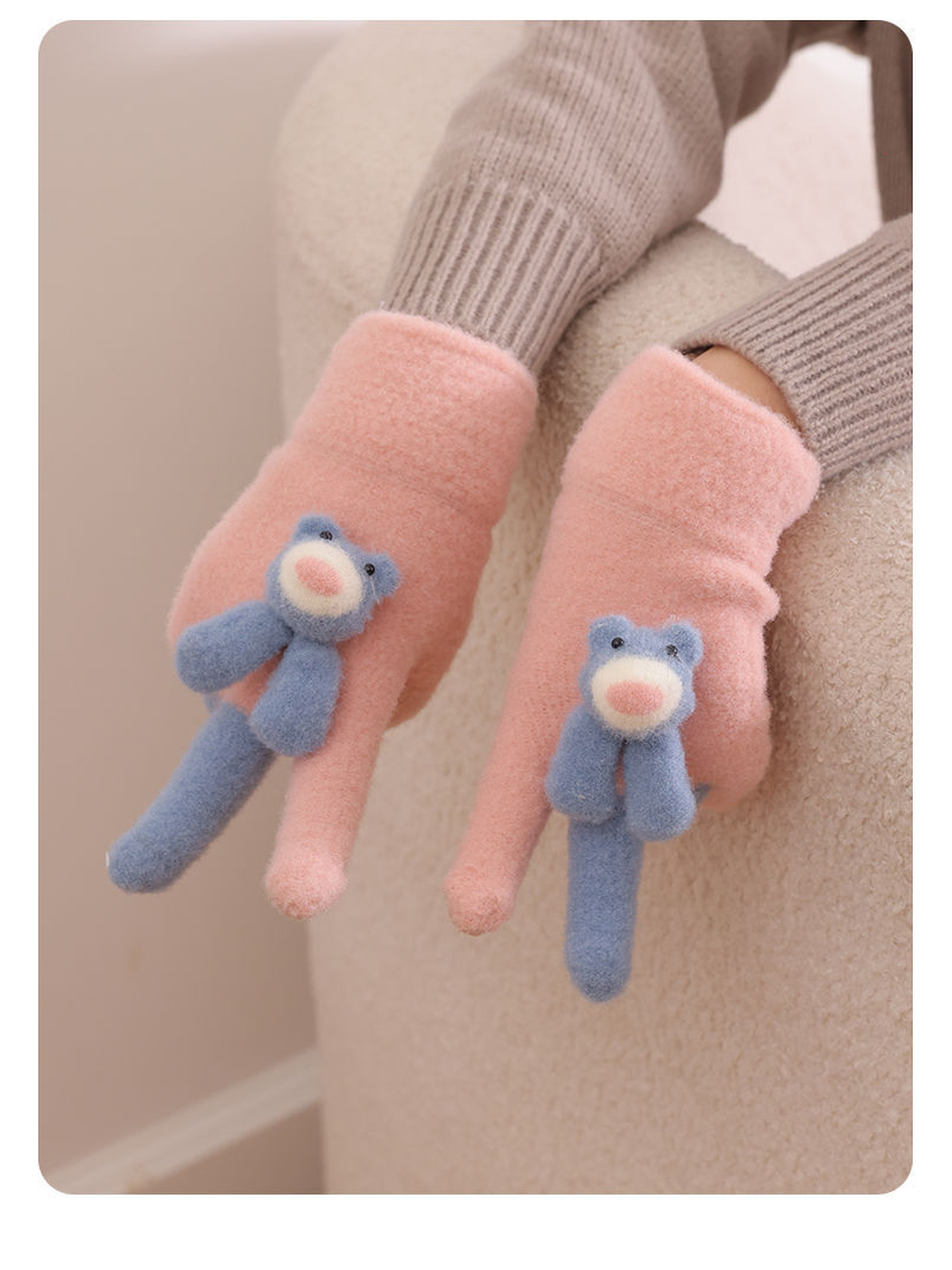 Pink fuzzy gloves with blue teddy bear appliques worn with a neutral sweater