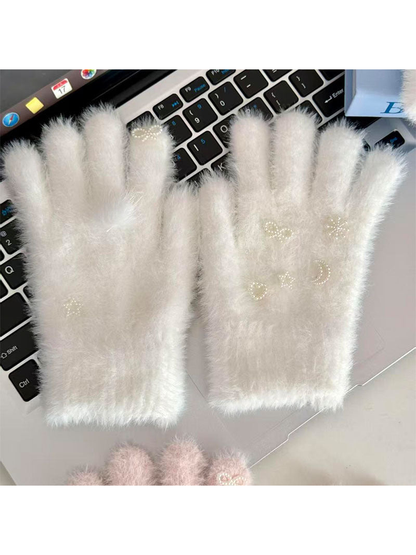 White fuzzy gloves with pearl-like celestial motifs displayed on a laptop