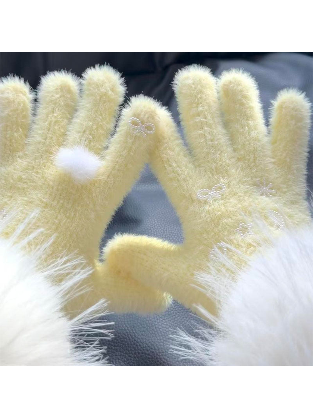 Close-up of Yellow fuzzy gloves with a fluffy pom-pom and pearl-like motifs