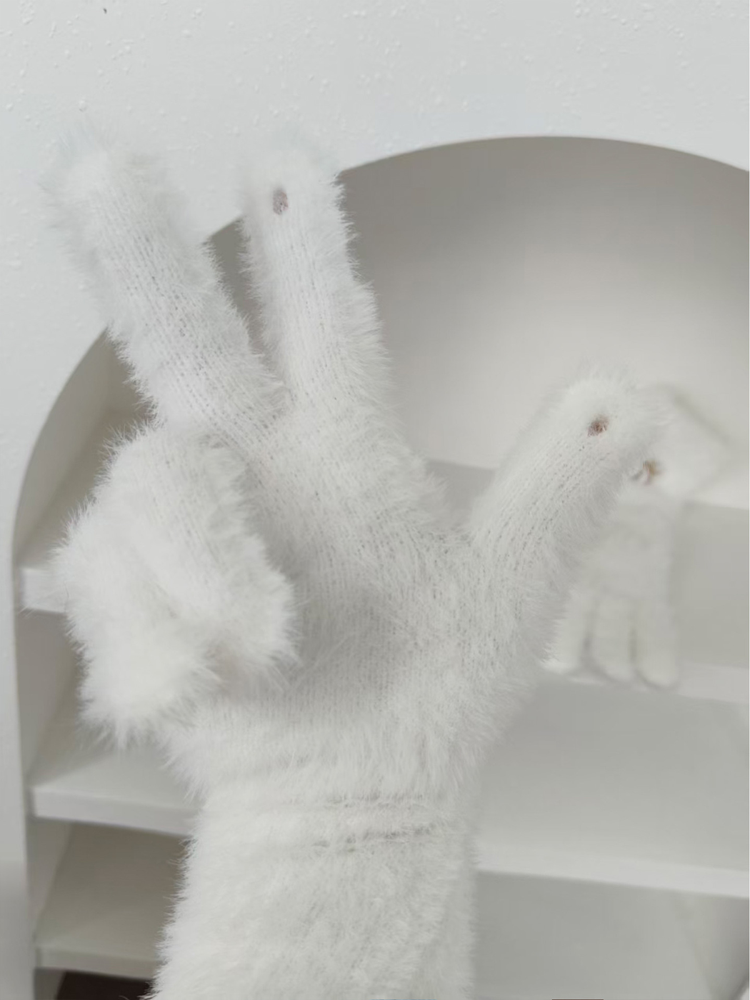 Close-up of white glove fingertip openings and fuzzy knit surface