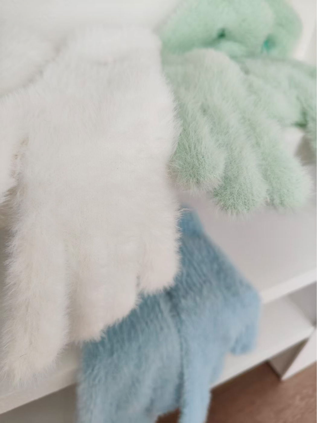 Close-up of fuzzy glove texture in white, mint and light blue