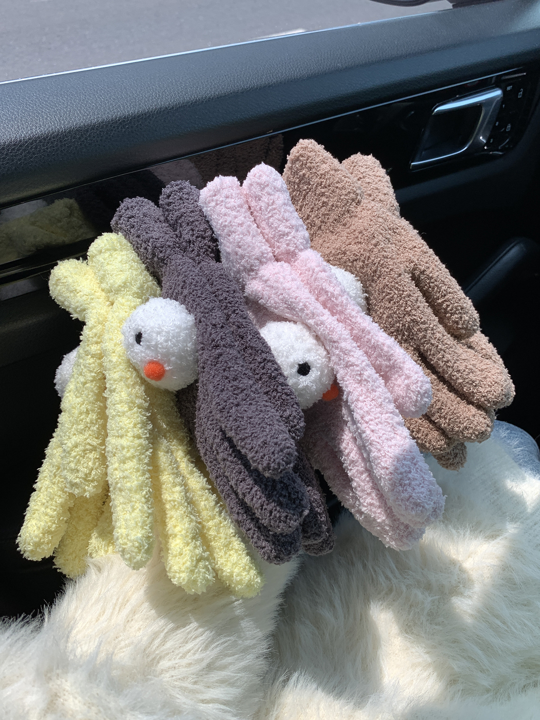 Yellow, gray, light pink and coffee snowman-face gloves stacked together