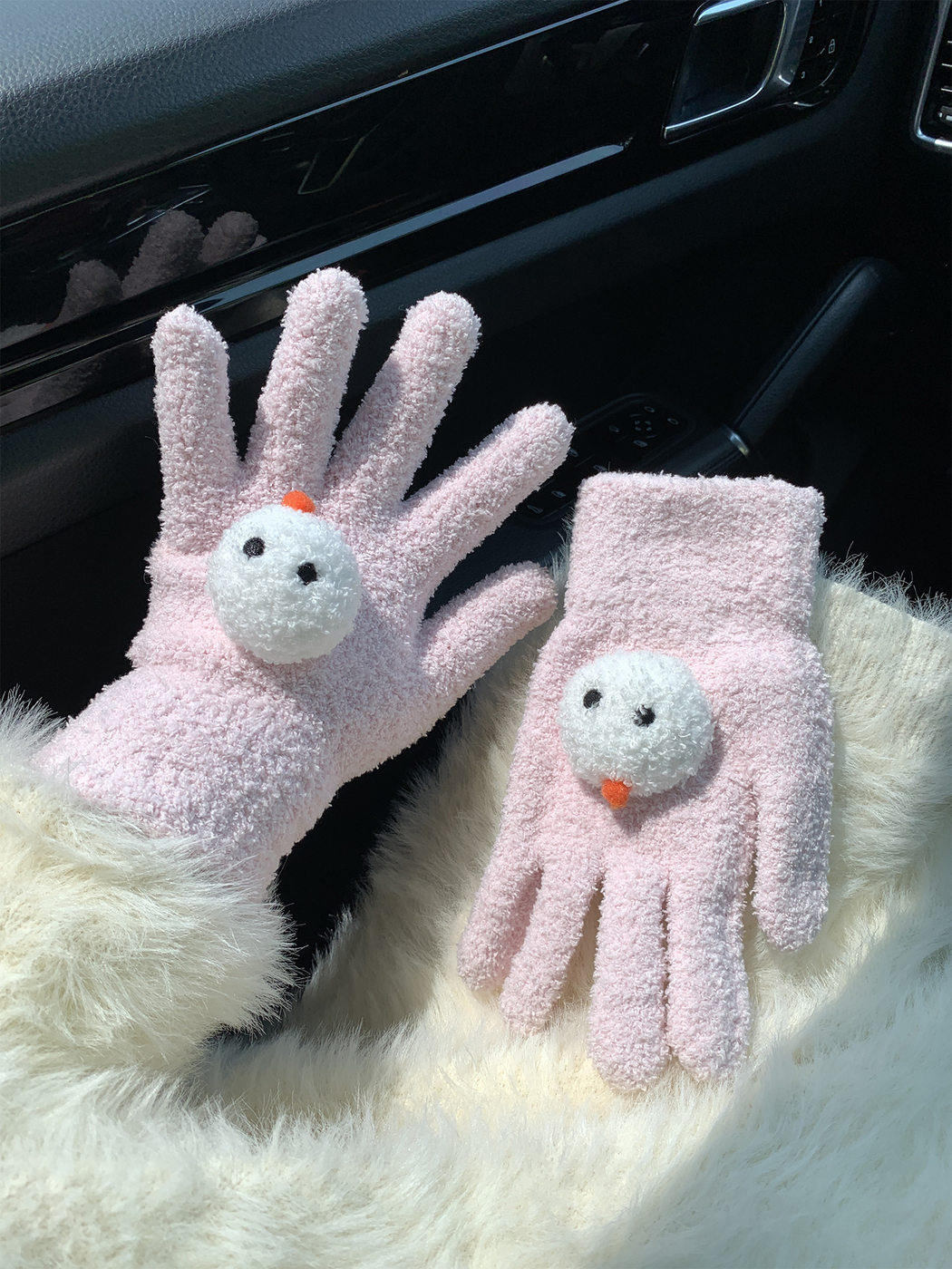 Light pink snowman-face gloves, one worn and one displayed flat