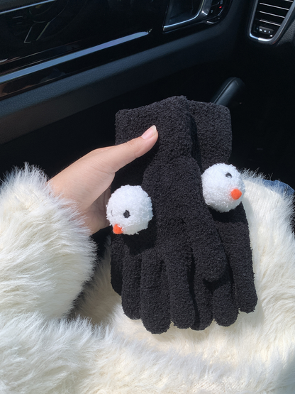 Black snowman-face gloves held together in a car interior