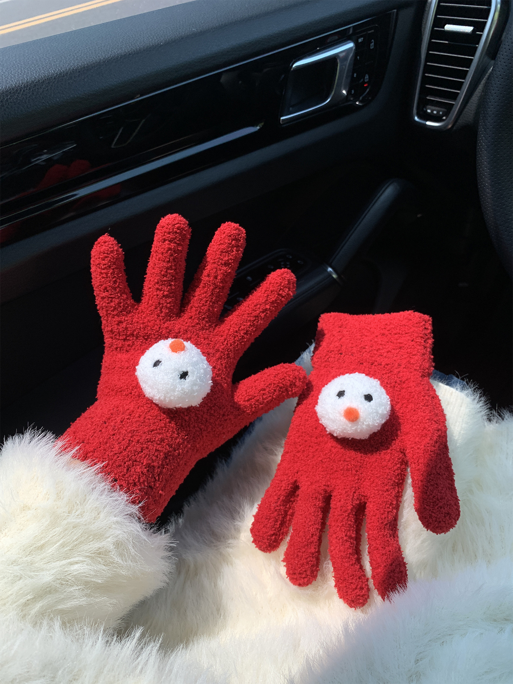 Red snowman-face gloves, one worn and one displayed flat