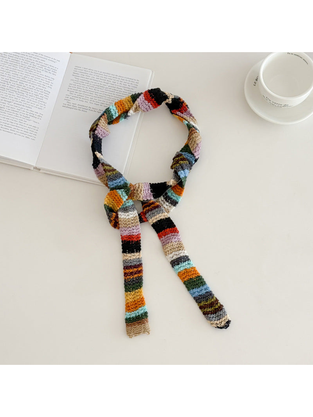 Multicolor striped narrow scarf tied loosely on a tabletop
