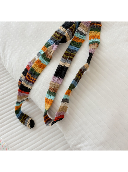 Close-up of the multicolor striped scarf draped over a quilted surface