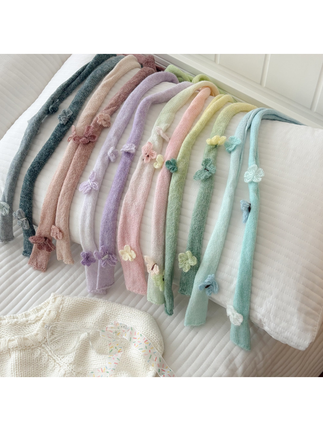 Multiple gradient knit scarves arranged over a white cushion