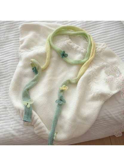 Green gradient knit scarf styled over a cream sweater