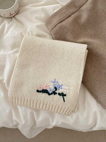 Ivory knit scarf folded to show the floral threadwork