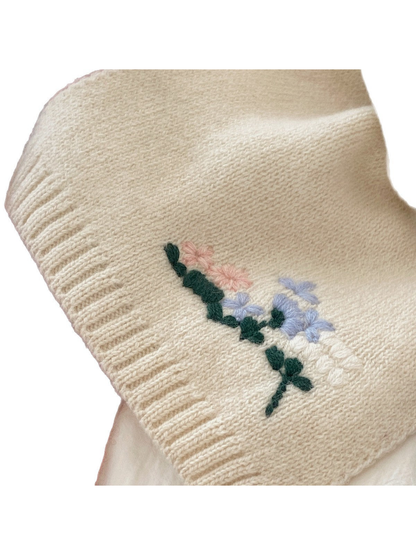 Close-up of the ivory scarf's floral threadwork and ribbed end