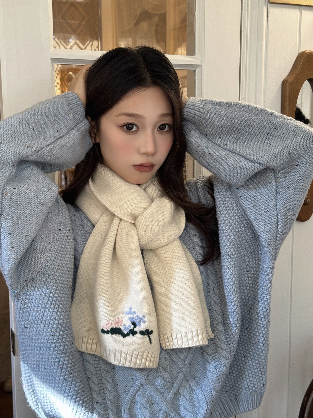 Ivory floral knit scarf worn with a light blue sweater