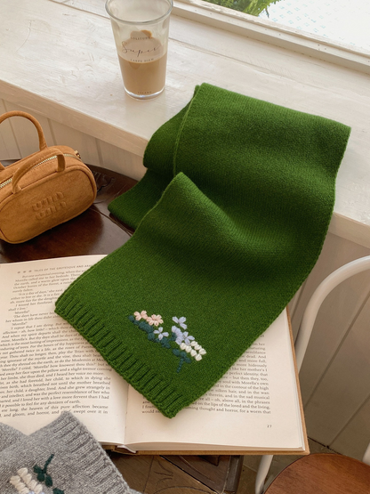 Green floral knit scarf draped across an open book