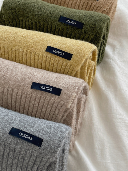 Close-up of stacked textured scarves with ribbed ends and fabric labels